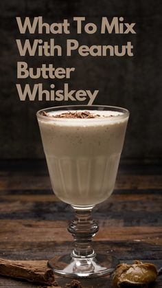 a glass filled with ice cream sitting on top of a wooden table next to a cookie