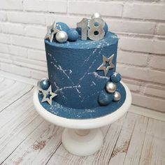 a blue cake with silver stars and numbers on it sitting on top of a white pedestal