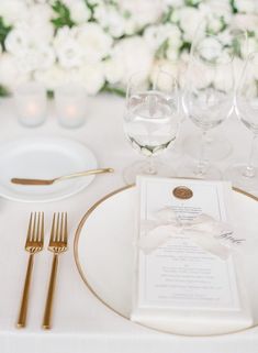 the table is set with white and gold place settings