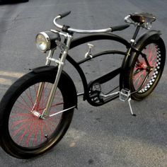 an old fashioned bicycle is parked on the street with red spokes and black tires