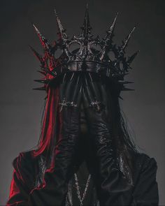 a man in black and red is wearing a crown with spikes on it's head