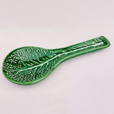 a green leaf shaped dish sitting on top of a white table