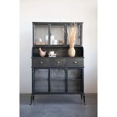 a black cabinet with glass doors and two vases on top