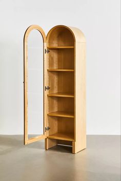 an arched wooden cabinet with mirror on the top and bottom shelf in front of it