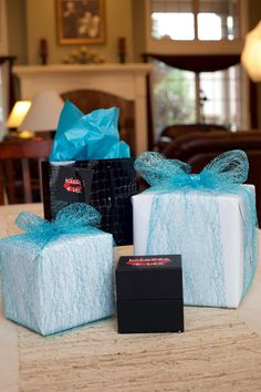 three wrapped presents sitting on top of a table next to a box with a blue ribbon