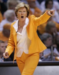 a woman in an orange suit and white shirt is on the court with her mouth open