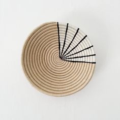 a woven basket with black lines on the bottom is shown in front of a white wall