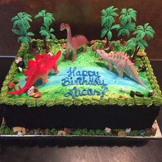 a birthday cake decorated with dinosaurs and palm trees