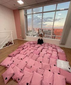 a person sitting on top of a bed made out of pink sheets with black hearts