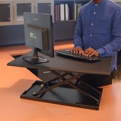 a man sitting at a desk with a keyboard and computer monitor on top of it