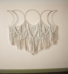 three crescents are hanging on the wall with macrame tassels attached to them