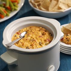 a white bowl filled with cheese and tortilla chips on top of a blue table