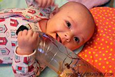 a baby laying on top of a bed with a bottle in it's hand