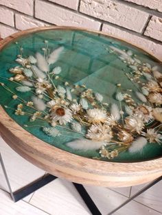 a wooden table topped with flowers on top of a white floor next to a brick wall