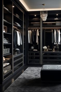 a walk - in closet with black cabinets and drawers, chandelier hanging from the ceiling