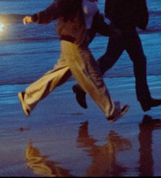 two people running on the beach at night