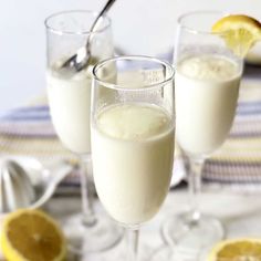 two glasses filled with white liquid next to sliced lemons