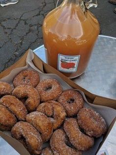 donuts and honey sit on a table next to a bottle of orange juice,