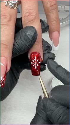 a woman is getting her nails done with red and white designs on it's fingers