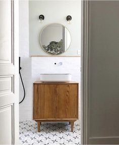 a bathroom with a sink, mirror and wooden cabinet next to it's door