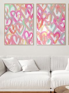 two abstract paintings hang on the wall above a white couch