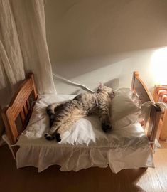 a cat laying on top of a bed next to a wooden table and chair in a room