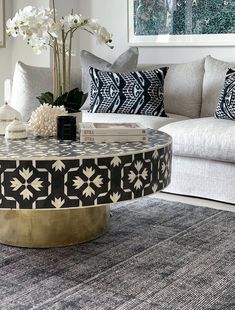 a living room with white couches and black and gold coffee table in the middle