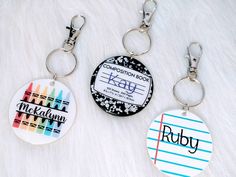 two key chains with different designs on them sitting on a white fur covered surface next to each other