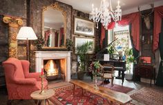 a living room filled with furniture and a chandelier hanging from the ceiling next to a fire place