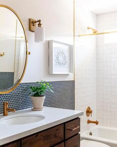 a bathroom with blue and white tiles on the walls, a round mirror over the bathtub, and a potted plant