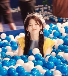 a girl in a ball pit with blue and white balls