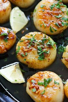 cooked scallops with lemon wedges and parsley in a skillet, ready to be eaten