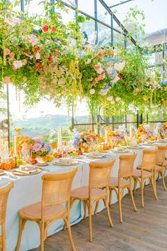 an outdoor dining area with tables, chairs and flowers hanging from the ceiling over them