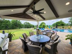 an outdoor dining area with patio furniture and large windows overlooking the pool in the back yard