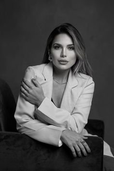 a black and white photo of a woman with her arms folded over her chest, sitting on a chair