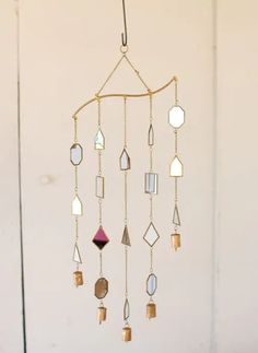 a wind chime hanging from the side of a wall with various shapes and colors