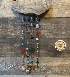 an assortment of beads hanging from the side of a wooden wall