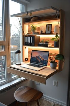 an open laptop computer sitting on top of a wooden desk in front of a window