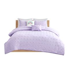 a bed with purple comforter and pillows on top of the headboard, in front of a white background