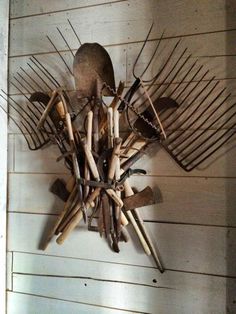 a clock made out of sticks and other items on a white wooden wall with wood slats attached to it