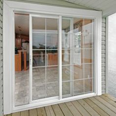 an open sliding glass door on the outside of a house with wood flooring and white siding