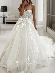 a woman in a wedding dress taking a selfie with her cell phone while standing in a white room