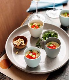 several bowls and cups on a tray with wine glasses