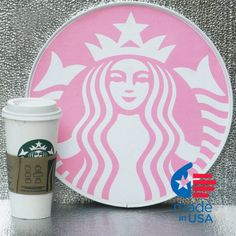 a cup of coffee next to a pink starbucks sign