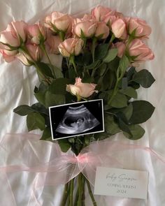 a bouquet of pink roses with a baby announcement