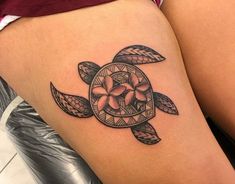 a woman's thigh with a turtle tattoo on the back of her leg and flowers in the center