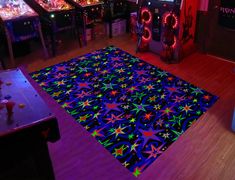 a brightly lit room with pinball machines and neon lights on the floor, along with an area rug