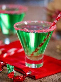 two glasses filled with green liquid and candy canes on top of a red napkin