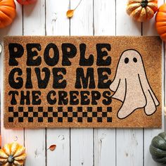 a door mat that says people give me the creeps on it next to pumpkins