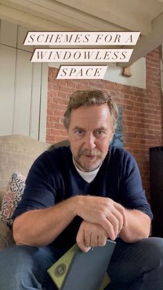 a man sitting on top of a couch next to a brick wall with the words scheme for a windowless space above him